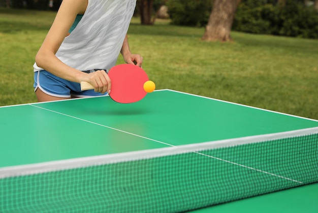 Mujer jugando al ping pong al aire libre en el primer plano del día de verano