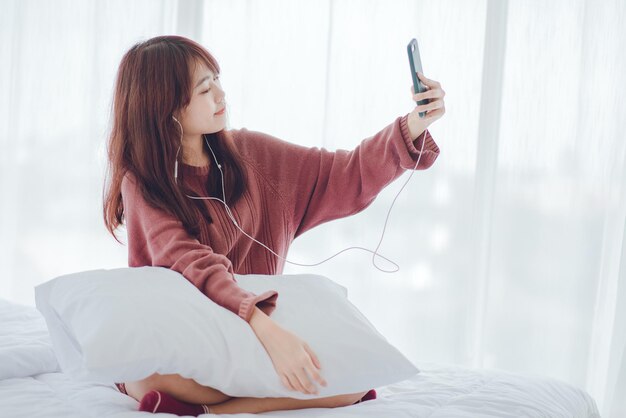 Una mujer jugando al teléfono en la cama de la casa.