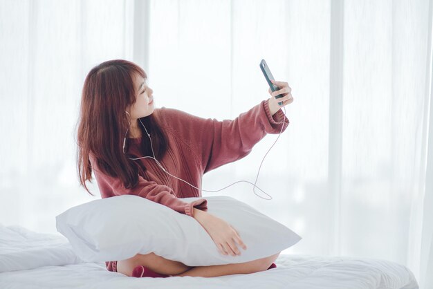 Una mujer jugando al teléfono en la cama de la casa.