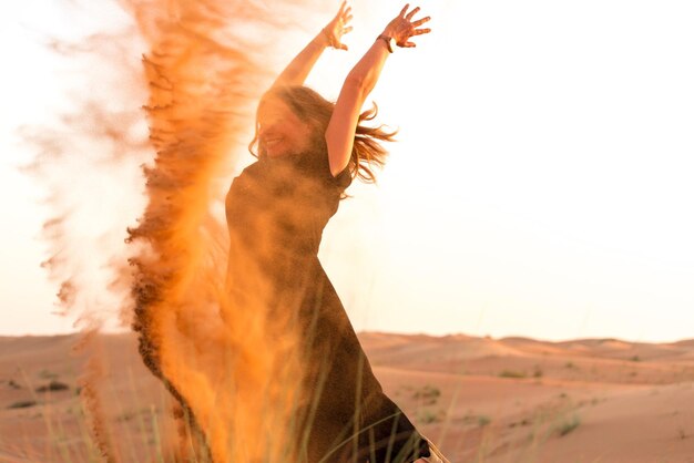 Foto mujer jugando con arena en el desierto contra un cielo despejado