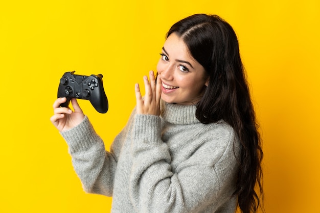 Mujer jugando con un controlador de videojuegos disuelto sobre fondo amarillo susurrando algo