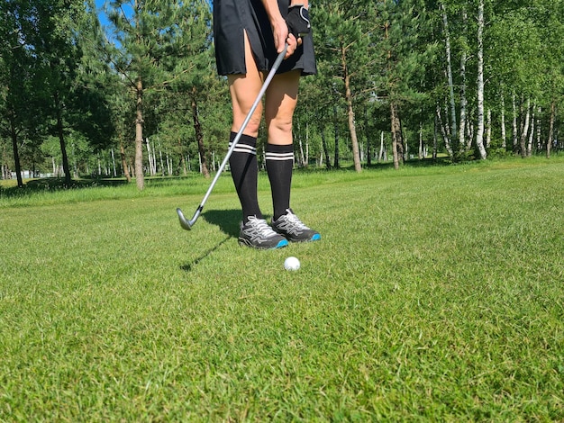 Mujer jugando golf vista de piernas y putter y pelota