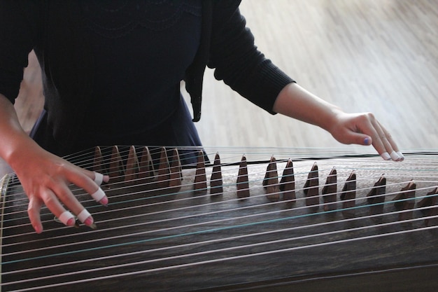 Mujer jugando a guzheng en el interior