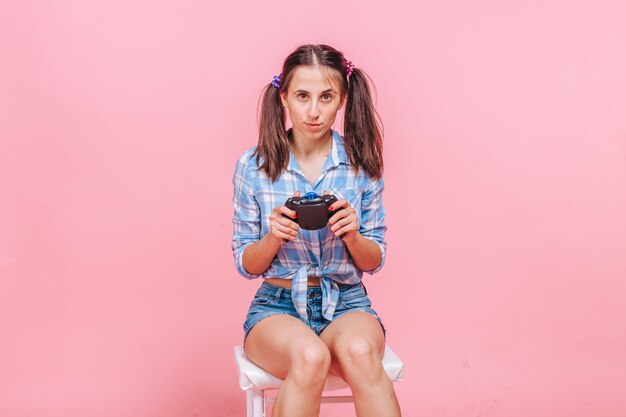 Mujer jugando juegos de computadora con joystick en pared rosa