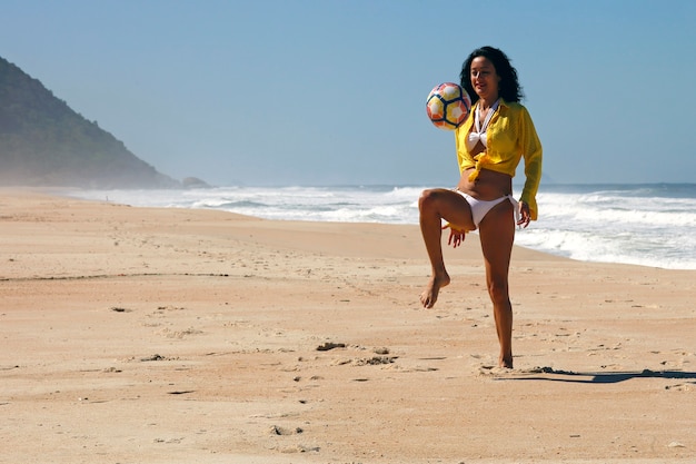 Mujer jugando a la pelota en la playa