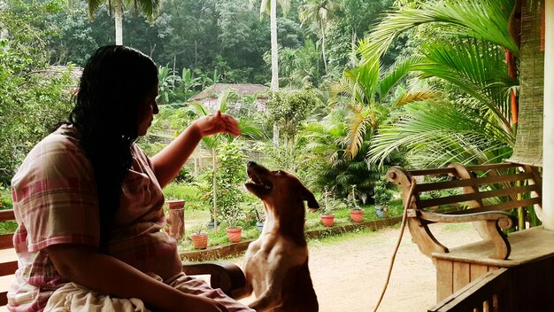 Foto mujer jugando con el perro mientras está sentada en el banco