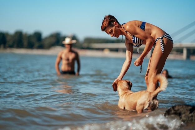 Mujer jugando con un perro en el río