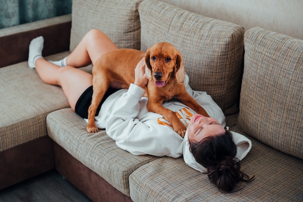 Mujer jugando con perro en el sofá acostado