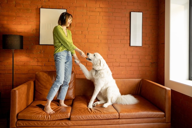 Mujer jugando con su lindo perro en un sofá en casa