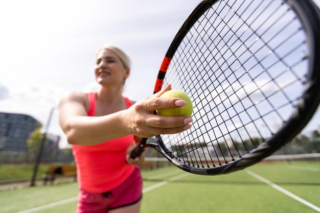 Mujer jugando tenis sosteniendo una raqueta y sonriendo