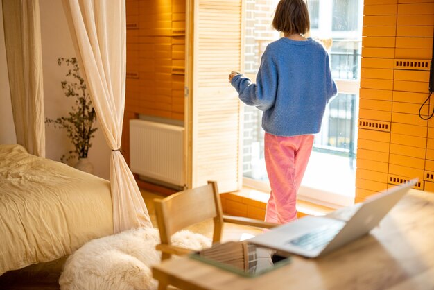 Mujer junto a la ventana en casa