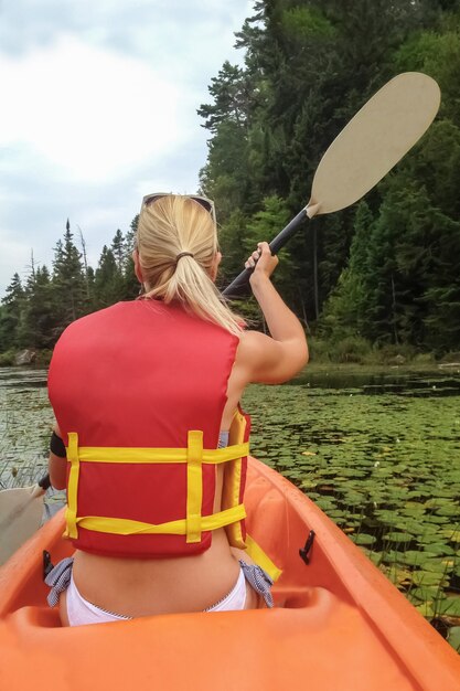 Mujer en kayak en el lago con nenúfares