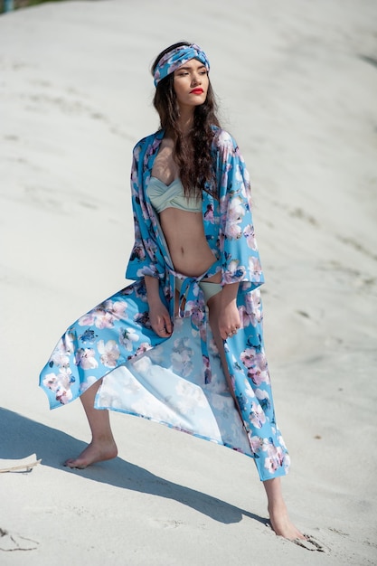 Una mujer con un kimono azul se encuentra en una playa.