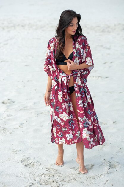 Una mujer con kimono se encuentra en la playa.