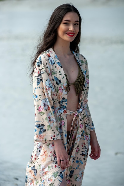 Una mujer con un kimono floral se encuentra en la playa.