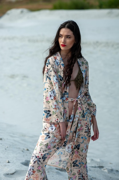 Una mujer con un kimono floral se encuentra en la playa.