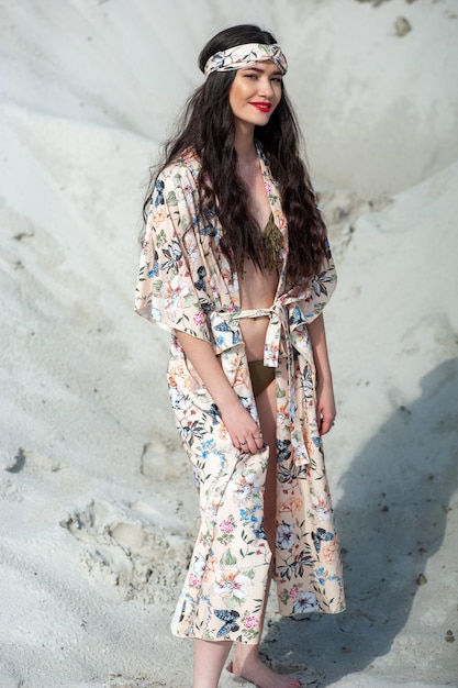 Una mujer con un kimono floral se encuentra en la playa.