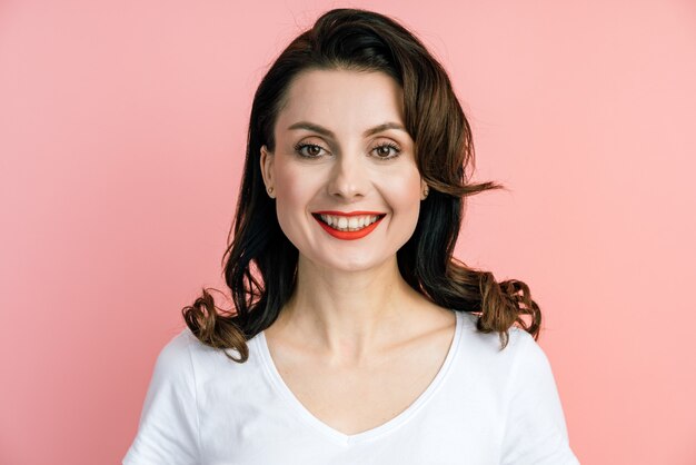 Mujer con labios rojos y una amplia sonrisa posando en el estudio.