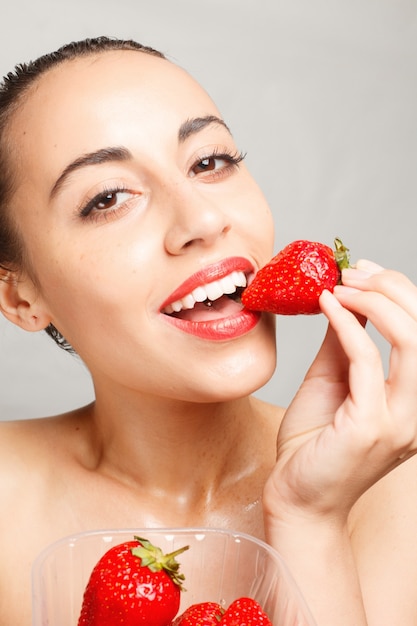 Mujer con labios rojos comiendo fresa