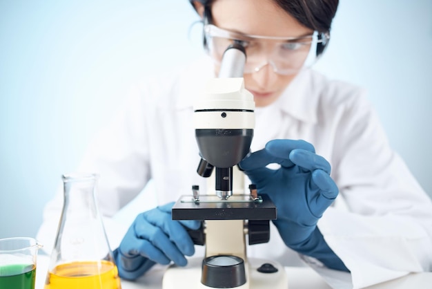 Mujer en laboratorio mirando a través de microscopio closeup ciencia biotecnología