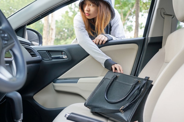 Mujer ladrón robar un bolso de hombro a través de la ventana del coche