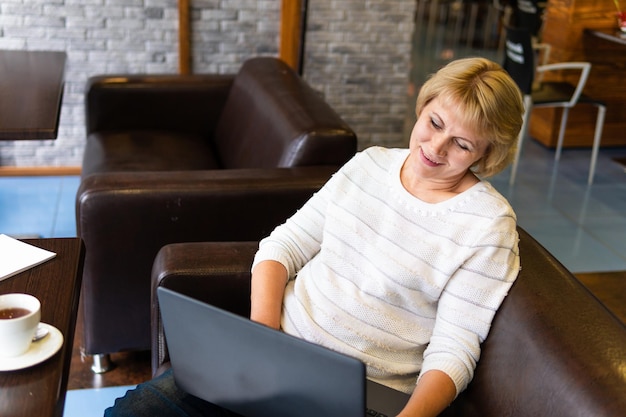 Una mujer con una laptop trabaja en un café en la oficina, es independiente.