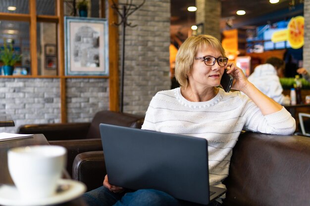 Una mujer con una laptop trabaja en un café en la oficina, es independiente.