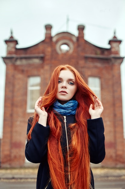 Mujer con largo cabello rojo camina en otoño en la calle