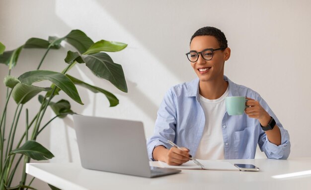 Foto mujer latina alegre, gerente, trabajadora independiente, disfruta de una taza de café.