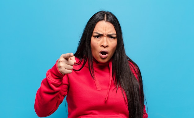 Mujer latina apuntando con una expresión agresiva enojada que parece un jefe loco y furioso