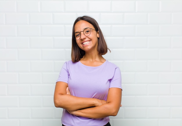 Mujer latina con aspecto de un triunfador feliz, orgulloso y satisfecho sonriendo con los brazos cruzados