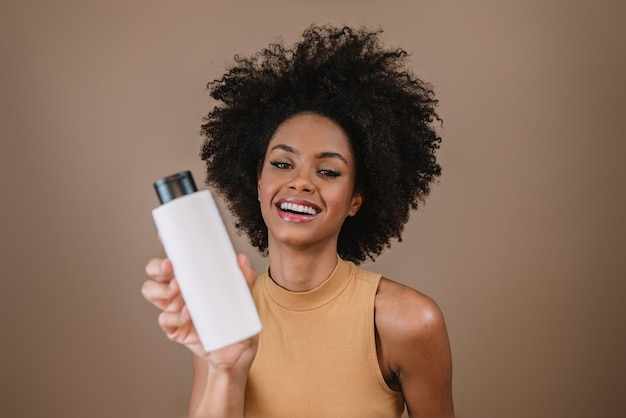 Mujer latina de belleza con peinado afro Mujer brasileña Sosteniendo envases de champú en blanco