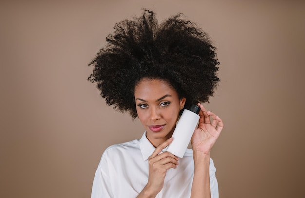 Mujer latina de belleza con peinado afro Mujer brasileña Sosteniendo envases de champú en blanco