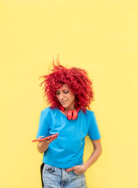 Mujer latina con cabello afro rojo envía mensajes de texto a través de un teléfono inteligente. concepto de estilo de vida en línea