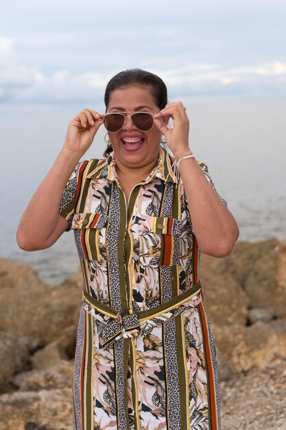 Mujer latina caminando por la calle mirando por encima de un par de gafas de sol