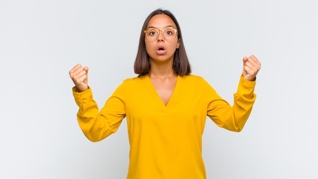 Mujer latina celebrando un éxito increíble como una ganadora, luciendo emocionada y feliz diciendo ¡toma eso!