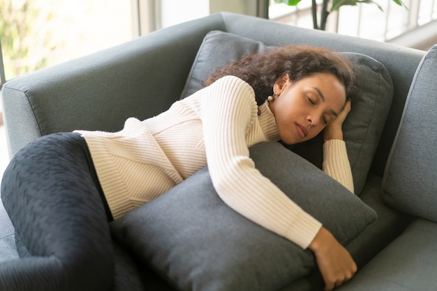 Mujer latina durmiendo en el sofá en casa