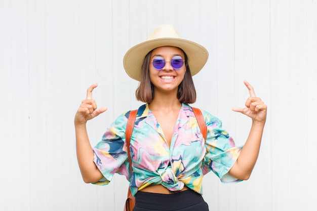 Mujer latina enmarcando o delineando su propia sonrisa con ambas manos, luciendo positivo y feliz, concepto de bienestar