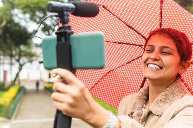 Una mujer latina se está tomando un selfie con su sombrilla en un pueblo