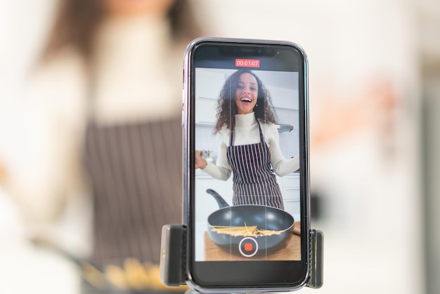 Mujer latina grabando video y cocinando en la cocina