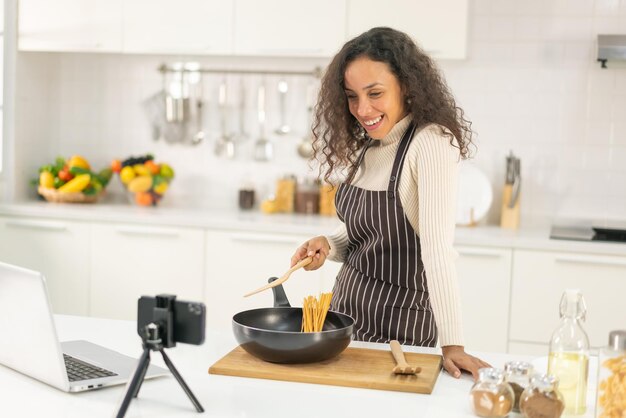 Mujer latina grabando video y cocinando en la cocina