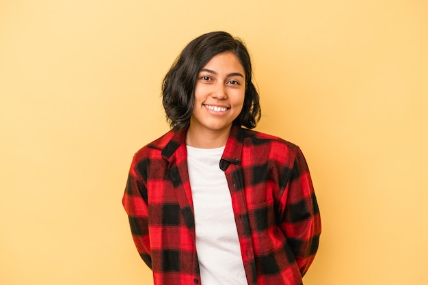 Mujer latina joven aislada sobre fondo amarillo feliz, sonriente y alegre.