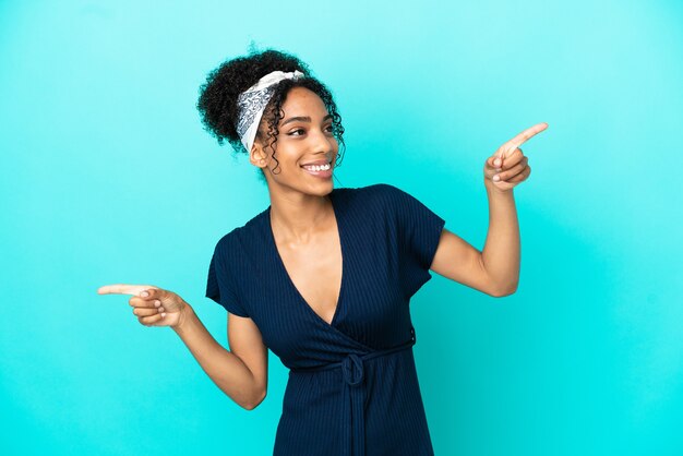 Mujer latina joven aislada sobre fondo azul dedo acusador a los laterales y feliz