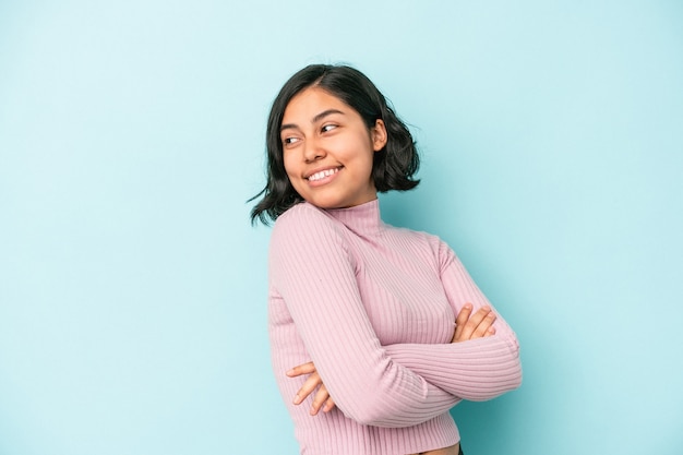 Mujer latina joven aislada sobre fondo azul riendo y divirtiéndose.