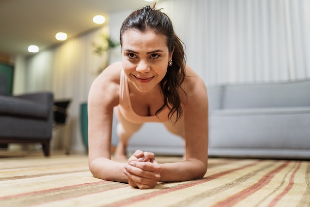 Mujer latina joven atractiva que hace yoga que estira yoga en casa. Concepto de estilo de vida saludable.