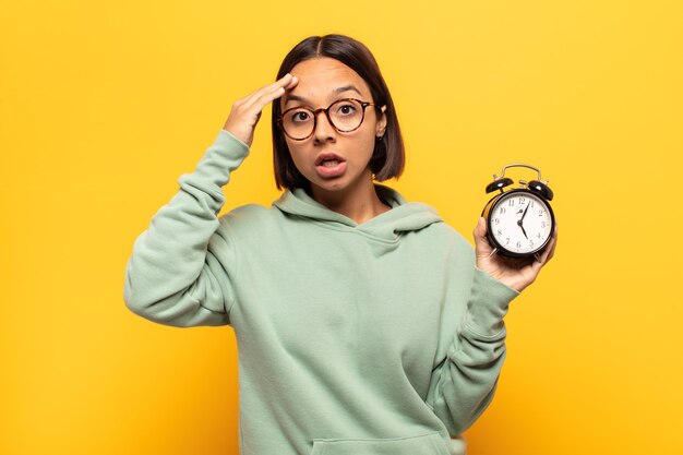 Mujer latina joven que parece feliz, asombrada y sorprendida, sonriendo y dándose cuenta de buenas noticias increíbles e increíbles