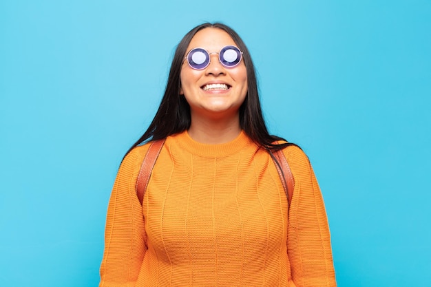 Mujer latina joven que parece feliz y tonta con una sonrisa amplia, divertida y chiflada y los ojos bien abiertos