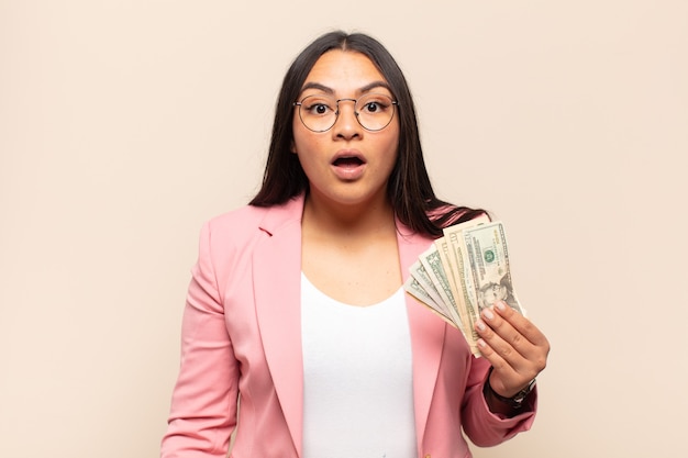 Mujer latina joven que parece muy conmocionada o sorprendida, mirando con la boca abierta diciendo wow