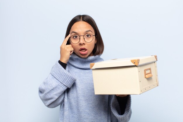 Mujer latina joven que parece sorprendida, con la boca abierta, conmocionada, dándose cuenta de un nuevo pensamiento, idea o concepto