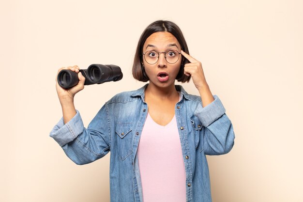 Mujer latina joven que parece sorprendida, con la boca abierta, conmocionada, dándose cuenta de un nuevo pensamiento, idea o concepto